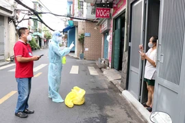 Thiếu úy Vũ Tiến Vũ, Bác sỹ Quân y Học viện Quân y (thứ 2 từ trái sang) thăm khám cho người dân tại đường Đất Thánh, phường 6, quận Tân Bình. (Ảnh: Xuân Khu/TTXVN) 