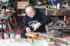 Ông Nguyễn Văn Cường (65 tuổi) là người thợ cao tuổi nhất của làng hàng ngày vẫn cần mẫn sửa kèn cho khách. (Ảnh: Nguyễn Lành/TTXVN) 