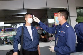 Đo thân nhiệt tại cửa soát vé tại bến xe Nước Ngầm (Hà Nội). (Ảnh: Danh Lam/TTXVN) 