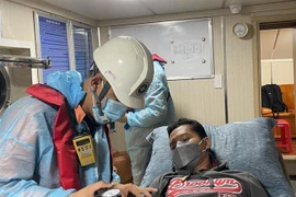 Thủy thủ người nước ngoài, anh Nuneza Japhet Cabahug (sinh năm 1986, quốc tịch Philippines) được các lực lượng cứu nạn, y tế kiểm tra sức khỏe trước khi đưa vào bờ điều trị. (Ảnh: TTXVN phát) 