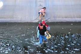 Người di cư vượt qua bức tường biên giới Mỹ-Mexico tại El Paso, Texas, Mỹ. (Ảnh: AFP/TTXVN)