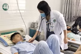Bác sỹ khám cho các học sinh bị nghi ngộ độc thực phẩm sau khi ăn cơm cuộn bán trước cổng trường. (Ảnh: Đinh Hằng/TTXVN)