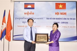 Ông Vũ Chiến Thắng, Trưởng Ban Tôn giáo Chính phủ tặng quà lưu niệm cho bà Min Chandyneth, Phó Quốc vụ khanh Bộ Lễ nghi và Tôn giáo Vương quốc Campuchia tại hội nghị. (Ảnh: Thanh Sang/TTXVN) 