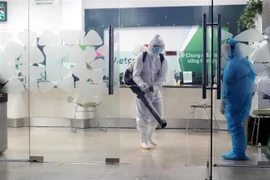 Lực lượng chức năng phun thuốc khử khuẩn trụ sở Ngân hàng Vietcombank, thành phố Thái Nguyên nơi chị T đã từng đến. (Ảnh: Trần Trang/TTXVN) 