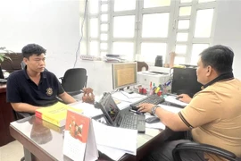 Công an làm việc với Phùng Thế Tài (áo đen) cầm đầu đường dây cá độ bóng đá. (Ảnh: TTXVN phát)