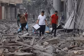 Người dân Palestine di chuyển qua đống đổ nát sau các cuộc không kích của Israel xuống Dải Gaza ngày 10/10/2023. (Ảnh: AFP/TTXVN)