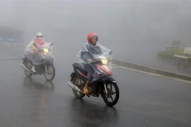 Người dân thị xã Sapa mặc áo mưa tránh rét. (Ảnh: Quốc Khánh/TTXVN)