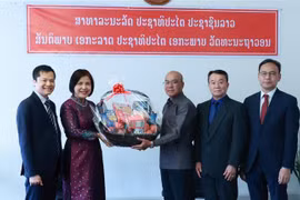 Đại sứ Lê Thị Tuyết Mai, Trưởng Phái đoàn thường trực Việt Nam (áo dài), chúc mừng Phái đoàn thường trực Lào tại Geneva. (Ảnh: Nguyễn Tuấn/TTXVN)