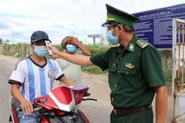 Lực lượng Bộ đội biên phòng đo thân nhiệt cho lao động vào cảng. (Ảnh: Phạm Cường/TTXVN) 