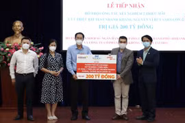 Ông Nguyễn Thành Trung, Phó Chủ tịch Thường trực Ủy ban Mặt trận Tổ quốc Việt Nam Thành phố Hồ Chí Minh tiếp nhận bảng tượng trưng sự ủng hộ của Tập đoàn Sovico, HDBank, Vietjet. (Ảnh: Xuân Khu/TTXVN) 