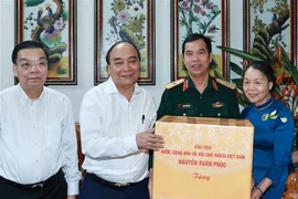 Chủ tịch nước Nguyễn Xuân Phúc đến thăm và tặng quà Thiếu tướng Hoàng Trung Kiên. (Ảnh: Thống Nhất/TTXVN)