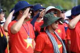 Các Kiều bào xúc động thực hiện nghi lễ chào cờ tại Quần đảo Trường Sa. (Ảnh: Thuỳ Giang/TTXVN)