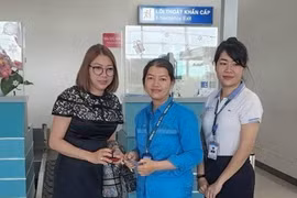 Chị Võ Thị Thùy Dung (giữa) bàn giao tài sản cho hành khách đánh rơi. (Ảnh: TTXVN phát)