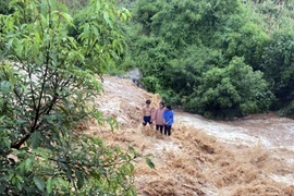 Ba cháu bé bị mắc kẹt giữa dòng lũ chảy xiết. (Ảnh: TTXVN phát)