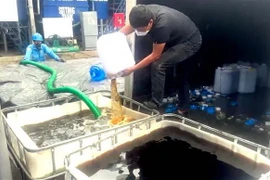 Lực lượng chức năng tiêu hủy số rượu không đảm bảo chất lượng. (Ảnh: TTXVN phát)