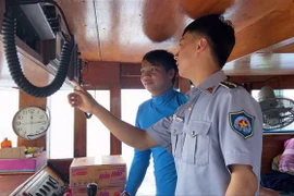 Kiểm ngư kiểm tra trang bị giám sát hành trình trên các tàu cá đang đánh bắt trên biển. (Ảnh: TTXVN phát)