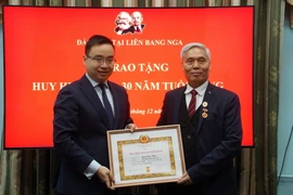 Ông Lưu Công Niệm (phải), Bí thư Chi bộ Docuchaev thuộc Đảng bộ tại Liên bang Nga, Chủ tịch Hội Cựu Chiến binh Việt Nam tại Liên bang Nga nhận Huy hiệu 50 năm tuổi Đảng. (Ảnh: Duy Trinh/TTXVN)