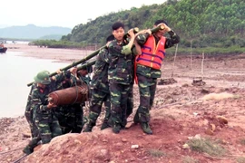 Lực lượng chức năng xử lý di chuyển quả bom đến nơi an toàn. (Ảnh: Nguyễn Hoàng/TTXVN)