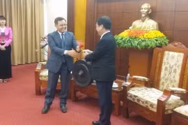 Bí thư Tỉnh ủy Hòa Bình Bùi Văn Tỉnh trao tặng chiếc chiêng Mường, sản phẩm văn hóa đặc sắc của Hòa Bình cho ông Saysomphone Phomvihane. (Ảnh: Nhan Sinh/TTXVN)