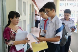 Giám thị coi thi đọc tên và số báo danh thí sinh tại địa điểm thi trường trung học phổ thông Bùi Thị Xuân (Quận 1). (Ảnh: Quang Nhựt/TTXVN)