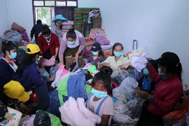 Đóng gói quần áo quyên góp tại trung tâm huyện Sanamsay để chuyển đến cho người dân vùng bị ảnh hưởng bởi sự cố vỡ đập. (Ảnh: Phạm Kiên/TTXVN)