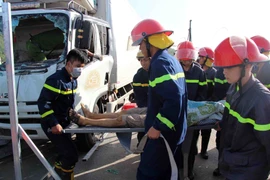 Đưa nạn nhân bị nạn kẹt trong cabin xe ra ngoài. (Nguồn: TTXVN phát)