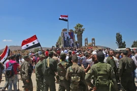Binh sỹ quân đội chính phủ Syria giương cao quốc kỳ sau khi giải phóng thành phố Quneitra ngày 27/7. (Nguồn: AFP/TTXVN)