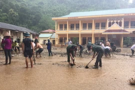 Hàng trăm người dầm mưa để kịp thời khắc phục hậu quả mưa lũ tại trường tiểu học Tà Hộc, huyện Mai Sơn. (Ảnh: Hữu Quyết/TTXVN)