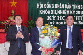 Ông Nguyễn Thanh Tùng, Bí thư Tỉnh ủy, Chủ tịch Hội đồng Nhân dân tỉnh Bình Định (phải) và ông Hồ Quốc Dũng, Chủ tịch Ủy ban Nhân dân tỉnh Bình Định tặng hoa chúc mừng ông Nguyễn Phi Long. (Ảnh: Phạm Kha/TTXVN)