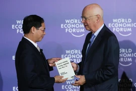 Giáo sư Klaus Schwab, Người sáng lập, Chủ tịch Điều hành Diễn đàn Kinh tế thế giới (bên phải) trao sách tặng Thứ trưởng Thường trực Bộ Ngoại giao Bùi Thanh Sơn. (Ảnh: Lâm Khánh/TTXVN)