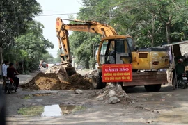 Chính quyền phường Vinh Tân huy động máy móc để san phẳng gạch đá, đảm bảo giao thông thông suốt trên đường Phạm Hồng Thái. (Ảnh: Tá Chuyên/TTXVN)