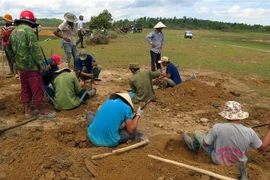 Một tốp người đang dùng xà beng, cuốc… để tìm đá đen. (Ảnh: Thế Lập/TTXVN)