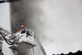 Lực lượng chữa cháy dùng xe thang tiếp cận hiện trường phun nước dập lửa. (Ảnh: Hoàng Ngà/TTXVN)