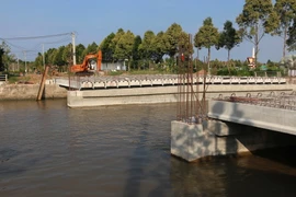 Công trình cầu Tân Hiệp bị phản ánh xây dựng quá thấp, tàu ghe không thể lưu thông, ảnh hưởng đến sinh hoạt, kinh doanh của hàng trăm hộ dân nơi đây. (Ảnh: Duy Khương/TTXVN)
