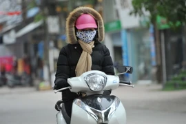 Trang phục kín mít của người dân khi ra đường để tránh rét. (Ảnh: Minh Đức/TTXVN)