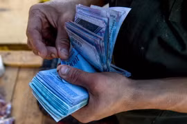 Người dân kiểm tiền Bolivar để mua hàng hóa tại Coche, Venezuela ngày 20/6. (Nguồn: AFP/TTXVN)