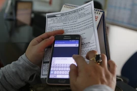 Hành khách nhắn tin qua điện thoại lấy số thứ tự để mua vé tàu Tết vào ngày 1/10. (Ảnh: Hoàng Hải/TTXVN)