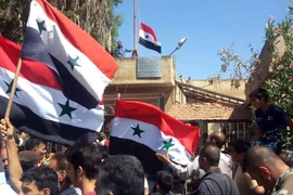 Người dân Syria giương cao quốc kỳ sau khi quân đội giành quyền kiểm soát tỉnh Daraa từ lực lượng nổi dậy ngày 12/7. (Nguồn: AFP/TTXVN)
