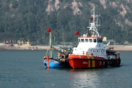 Tàu SAR 273 của Trung tâm Phối hợp tìm kiếm cứu nạn hàng hải Việt Nam (màu vàng) đang lai dắt tàu NA 93018 TS (màu xanh) vào bờ. (Ảnh: Tá Chuyên/TTXVN)
