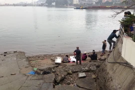 Thi thể nạn nhân được đưa vào bến phà cũ. (Ảnh: Trung Nguyên/Vietnam+)