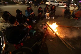 Người dân quây quần bên đống lửa để sưởi ấm. (Ảnh: Phan Tuấn Anh/TTXVN)