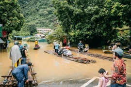 Tuyến đường thuộc thị trấn Pác Mjầu, huyện Bảo Lâm bị ngập sâu, người dân phải dùng bè mảng để di chuyển. (Ảnh: Bảo Chung/TTXVN phát)