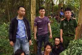 Ba đối tượng trồng cây thuốc phiện (ngồi) bị tạm giữ hình sự cùng số tang vật. (Ảnh: TTXVN)