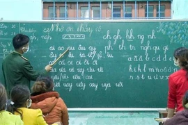 Chiến sỹ biên phòng giúp phụ nữ đồng bào dân tộc Pa Cô-Vân Kiều trên địa bàn xã A Dơi, huyện Hướng Hóa (Quảng Trị) biết đọc, biết viết. (Ảnh: TTXVN)