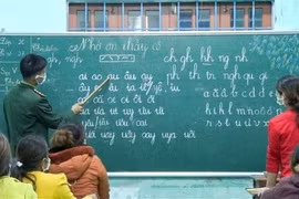 Chiến sỹ biên phòng giúp phụ nữ đồng bào dân tộc Pa Cô-Vân Kiều trên địa bàn xã A Dơi, huyện Hướng Hóa (Quảng Trị) biết đọc, biết viết. (Ảnh: TTXVN)
