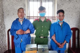 Hai đối tượng cùng tang vật tại cơ quan Công an. (Ảnh: TTXVN phát)