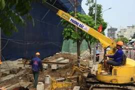 Công ty cổ phần Phương Bắc đang thực hiện đào đất để đổ bê tông trụ móng, đưa cẩu tháp vào phá dỡ 8B Lê Trực. (Ảnh Mạnh Khánh/TTXVN)