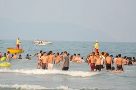 Đội viên của đội cứu hộ túc trực bằng thuyền thúng trên biển để đảm bảo an toàn cho người dân và du khách tắm biển Đà Nẵng. (Ảnh: Đinh Văn Nhiều/TTXVN) 