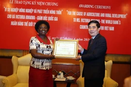 Bộ trưởng Nông nghiệp và Phát triển Nông thôn Cao Đức Phát trao kỷ niệm chương cho bà Victoria Kwakwa. (Ảnh: Vũ Sinh/ TTXVN) 