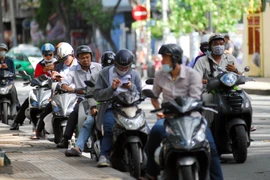 Nhiều người dừng xe máy và điều khiển xe máy trên đường để tìm bắt Pokemon ảo. (Ảnh minh họa: Mạnh Linh/TTXVN)